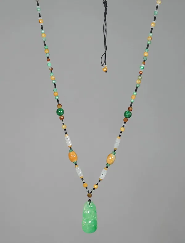 A Chinese jade necklace, 20th century, formed of circular and tubular beads of various colours and size, suspending a jadetite pendant carved with a s