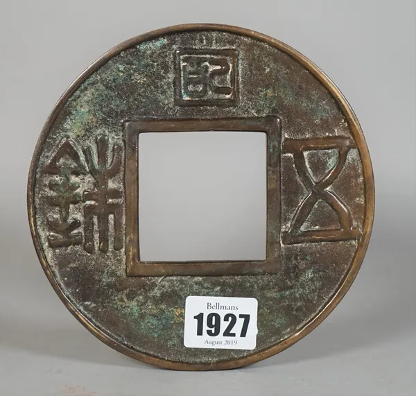 A Chinese bronze bi disc, each side cast with symbols around a square aperture, 15cm.diameter.