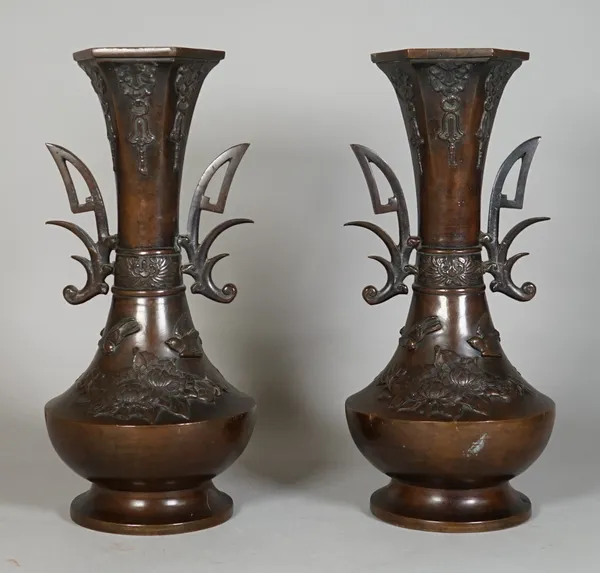 A pair of Japanese bronze two-handled vases, Meiji period, of bottle form beneath a slender neck and hexagonal rim, each decorated in relief with bird