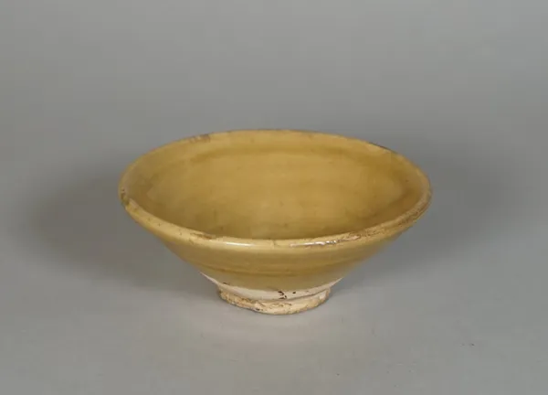 A small Chinese pottery bowl ,probably Tang dynasty, covered in a straw coloured glaze, 11cm. diameter.