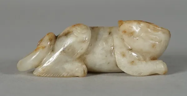 A Chinese cream and russet jade figure of a recumbent cat, Qing Dynasty, the stone with grey inclusions, 5.5cm. length.