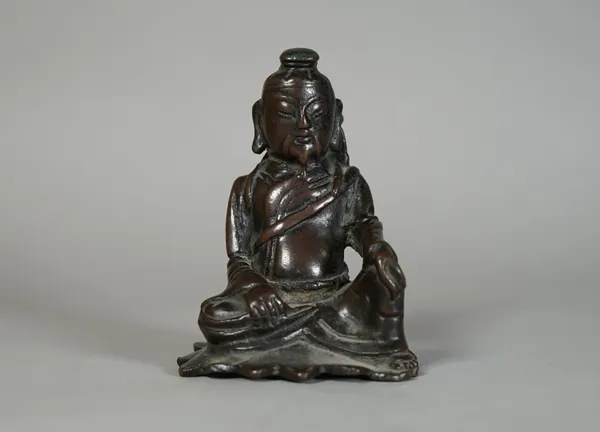 A small Chinese bronze figure of a warrior, probably Ming dynasty, modelled seated with left hand resting on knee and carrying a sword on his back, 8.