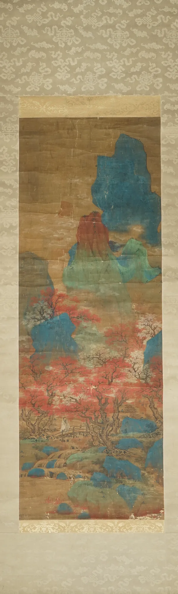 A Japanese scroll painting on silk, 19th century, watercolour on paper, painted with a figure in a mountainous landscape, 140cm. by 50cm.