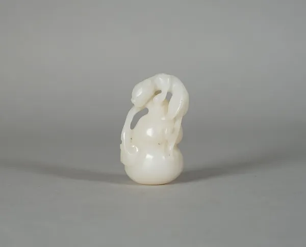 A Chinese white jade group, carved as a chliong clambering up a double gourd, 5cm. high.