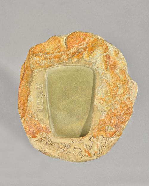 A Chinese carved inkstone, possibly 18th century, of irregular form, carved at the top with branches of pine and incised down one side of the recess w