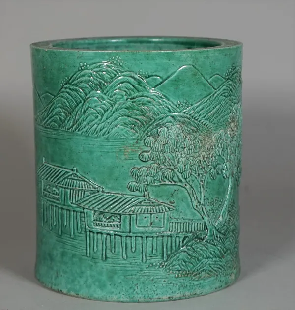 A Chinese green-glazed cylindrical brushpot in the style of Wang Bingrong, late 19th/20th century, decorated in low relief with a river landscape with