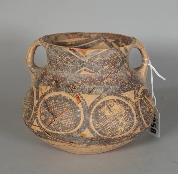 A Chinese painted red earthenware two-handled jar, Neolithic period, of squat form, painted with stylised designs, (a.f), 12.5cm. high.