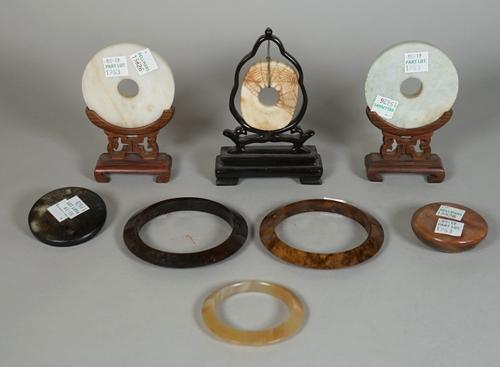 A group of Chinese jades, various colours and dates, comprising; a cream and brown oblong bi disc incised with a web pattern, 5.5cm. high, wood stand;