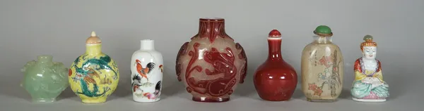 A group of seven Chinese snuff bottles, various materials including a porcelain seated buddha, 7cm. high; a red overlay glass bottle, 9.5cm. high; a p