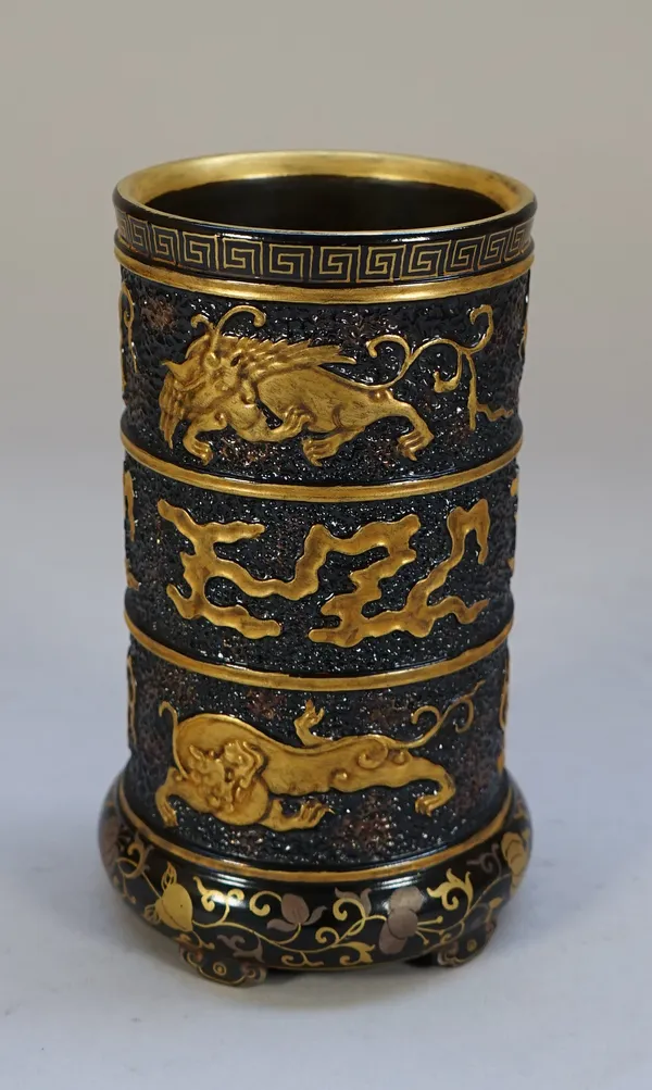 A Chinese porcelain cylindrical brush pot, Qianlong seal mark but later, made to imitate bronze and lacquer, moulded with bands of gilded mythical bea