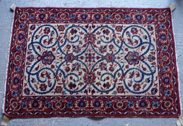 An Isfahan rug, Persian, the ivory field with a central flowerhead, other palmettes and indigo scrolling tendrils/ floral sprays, a madder palmette an