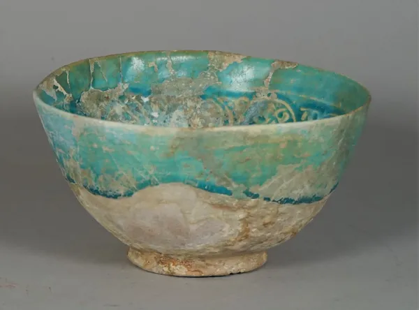 A Kashan turquoise glazed pottery bowl, probably 12th century, the interior moulded with a continuous foliate band, (a.f), 16cm. diameter.