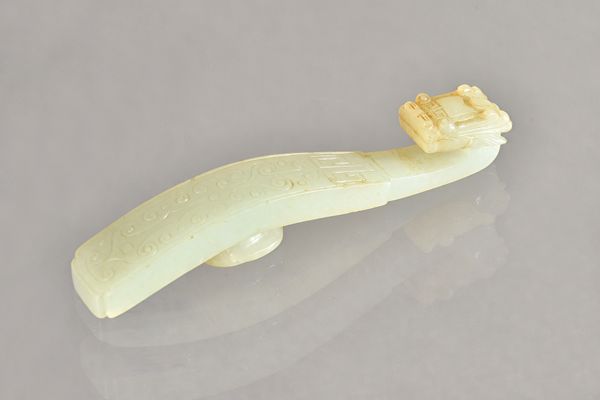 A Chinese pale celadon jade belthook, probably 19th century, carved with a dragon's head terminal, the shaft lightly carved with archaistic scrolls, t