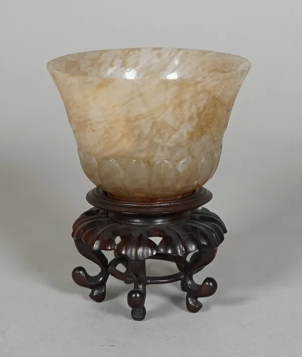 A Chinese agate teabowl, 19th/20th century, carved with lappets beneath a stiff leaf border, the stone with cream and russet inclusions, 4.5cm. high,