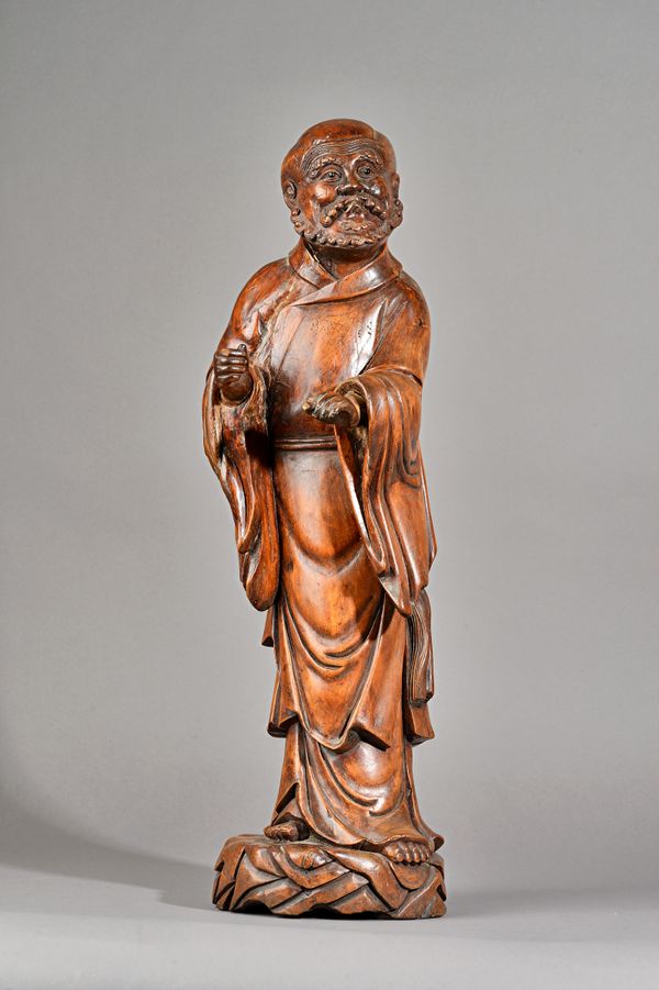 A large Chinese carved wood figure of Damo, the Buddhist divinity standing in long robes with a benevolent expression on his face, 62cm. high, wood st