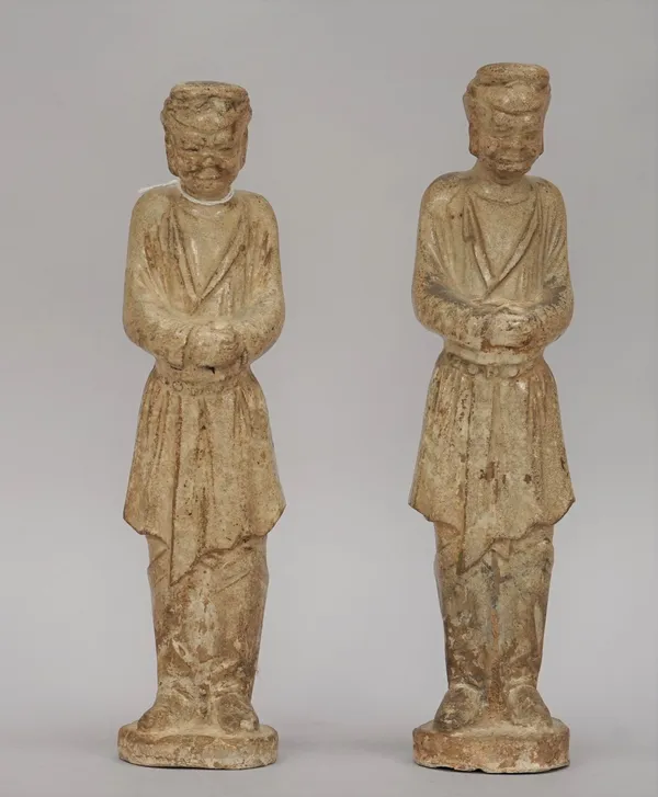 A pair of Chinese pottery figures of grooms, Sui/Tang dynasty or later, each male standing with head down and hands clasped, each approx. 26cm.high, (