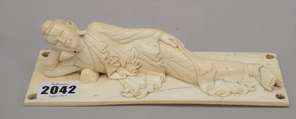 A Burmese ivory figure of Buddha, late 19th/early 20th century, carved in recumbent pose with her right hand supporting her head, the flat rectangular