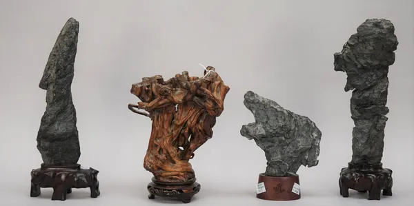 Three Chinese scholar's rocks, of irregular form and dark grey tone, 14cm. to 26cm. high, wood stands; also a rootwood sculpture, 19cm. high, wood sta