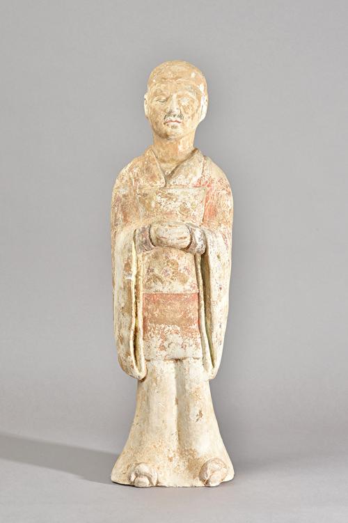 A tall Chinese painted pottery figure of an official, probably Tang dynasty, standing in long robes with eyes closed and hands clasped, traces of red