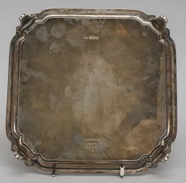 A silver salver, of shaped square form, raised on four tapered curved legs, presentation inscribed to the centre, Sheffield 1934, 20cm across, weight