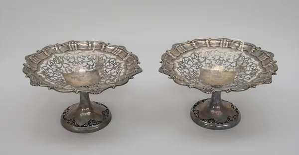 A pair of silver sweetmeat stands, each of shaped circular form, with a shell and pie-crust rim, otherwise with pierced decoration, raised on a pierce