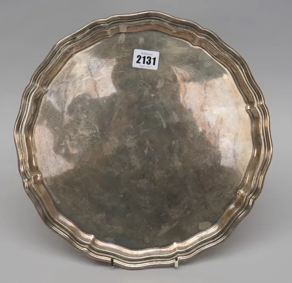 A silver salver, of shaped circular form, having a pie-crust rim, raised on three scrolling feet, diameter 31.5cm, Sheffield 1918, weight 1115 gms.