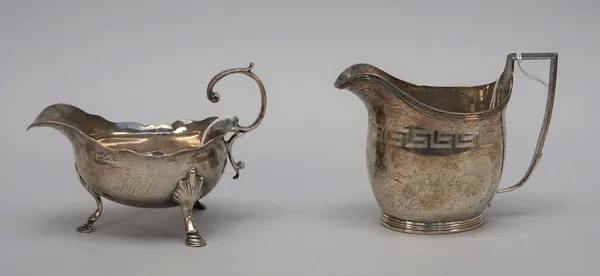 A George III sauce boat, having a shaped rim, scrolling handle and raised on three hoof shaped feet, London 1762 and a George III cream jug, of helmet