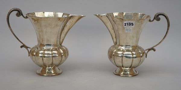 An Italian jug of panelled form with a scrolling handle, raised on a circular foot, detailed 800, height 18cm and another similar jug, both with remai