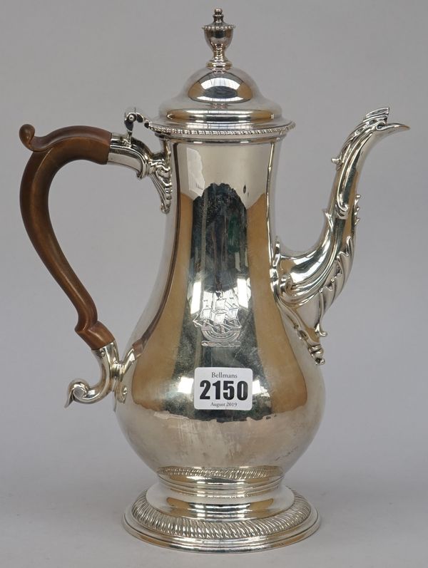 An early George III silver coffee pot, of baluster form, decorated with gadrooned rims, the hinged lid with a beaded urn finial, the body crest engrav