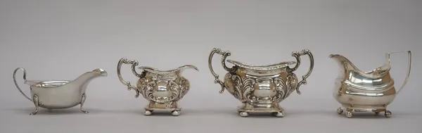 Silver, comprising; a twin handled sugar bowl, with foliate embossed decoration, scrolling handles and raised on bun feet, Chester 1903, a milk jug in