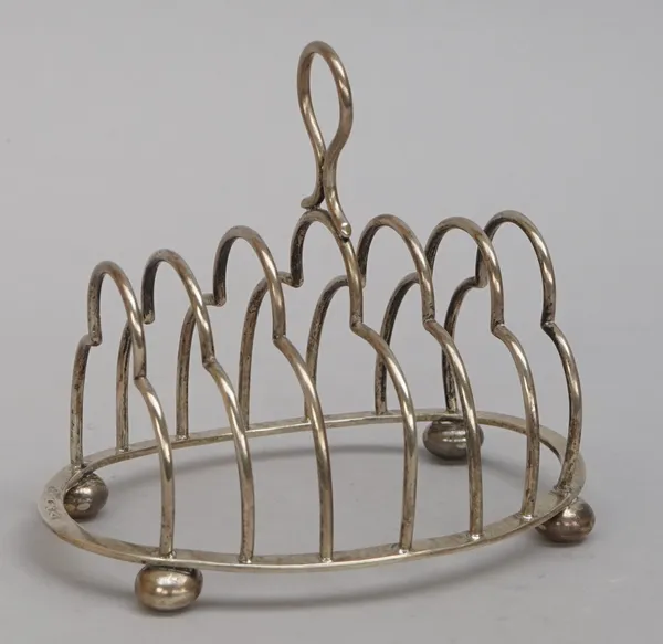 A late Victorian silver seven bar toastrack, of curved form with a loop handle, raised on an oval base, having four bun feet, Birmingham 1891, weight