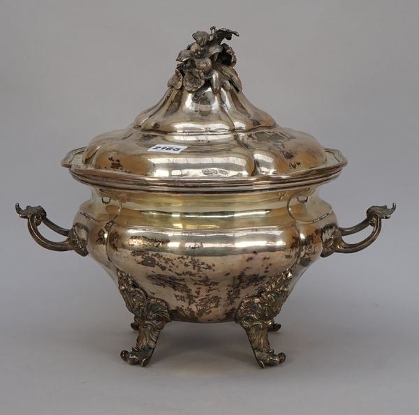 An Italian twin handled tureen and cover, of shaped baluster form, raised on four bold scrolled feet, the detachable cover with a floral finial within