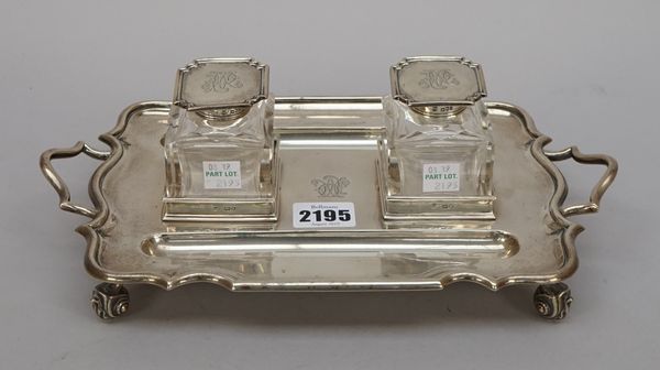 A silver twin bottle inkstand, of twin handled, shaped rectangular form, monogram engraved, raised on four scrolled feet, length 29.5cm, London 1901,