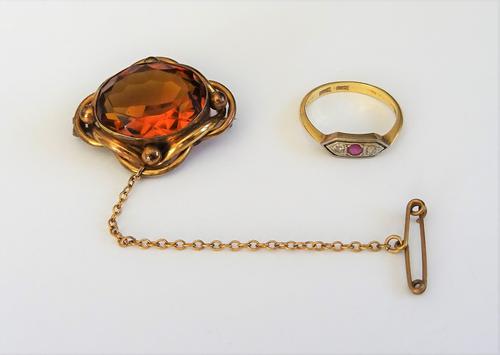 A gold and platinum, ruby and diamond set three stone ring, mounted with the cushion shaped ruby to the centre, between two smaller cushion shaped dia