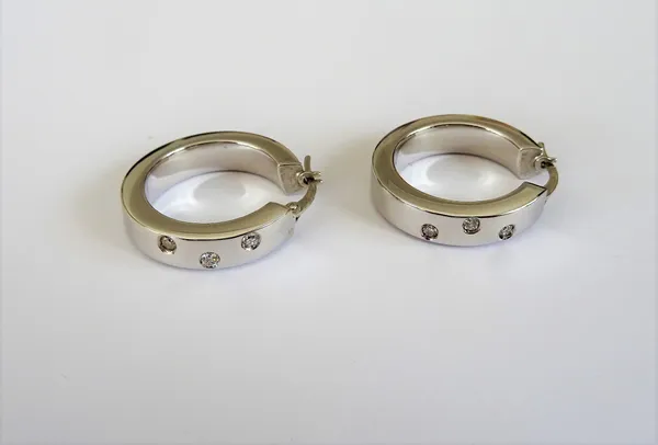 A pair of 18ct white gold and diamond set earrings, each in a circular hoop shaped design, mounted with three circular cut diamonds, gross weight 7.6
