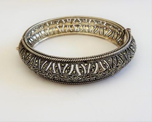 A silver and marcasite set circular hinged bangle, having pierced decoration within twin wirework borders, on a snap clasp, detailed 925, gross weight