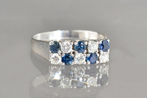 A white gold, diamond and sapphire ring, mounted with two rows of five alternating claw set circular cut diamonds and circular cut sapphires, detailed