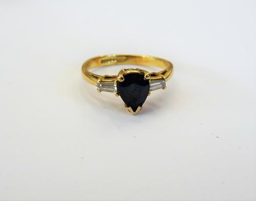 An 18ct gold, sapphire and diamond three stone ring, claw set with the pair shaped sapphire to the centre, between two tapered baguette diamonds, ring