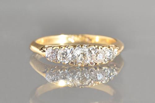 A gold and diamond five stone ring, mounted with a row of five principal cushion shaped diamonds graduating in size to the centre stone and with four