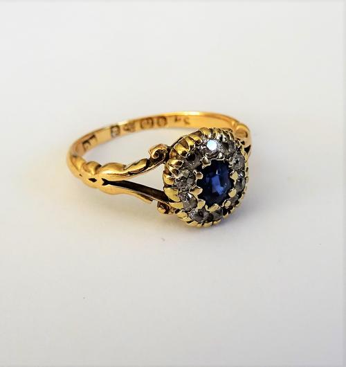 A late Victorian 18ct gold, sapphire and diamond set oval cluster ring, mounted with the oval cut sapphire to the centre, in a surround of ten cushion