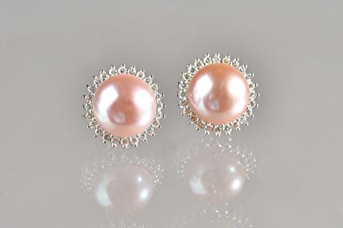 A pair of white gold, diamond and culutred pearl earstuds, each mounted with a large cultured pearl to the centre, within a surround of small circular