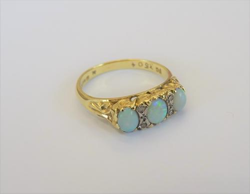 An 18ct gold, opal and diamond ring, mounted with three oval opals and with two pairs of small cicular cut diamonds, mounted at intervals, the mount d