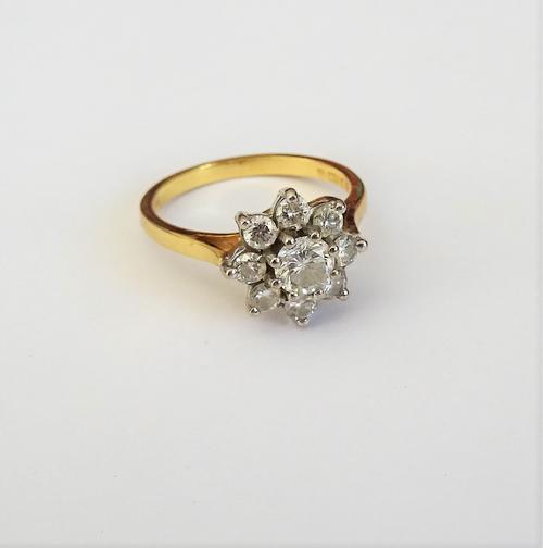 An 18ct gold and diamond nine stone cluster ring, claw set with the principal circular cut diamond at the centre, in a surround of eight smaller circu