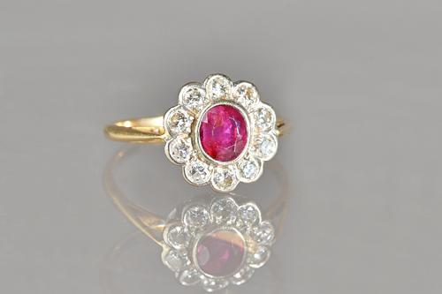A gold, ruby and diamond set oval cluster ring, collet set with the oval cut ruby to the centre, in a surround of ten circular cut diamonds, detailed