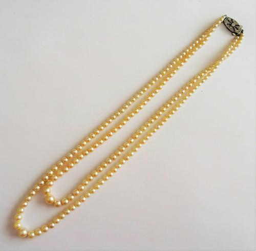 A two row necklace of cultured pearls, graduating in size to the front on a Sterling silver and colourless paste set clasp, with a case.
