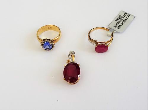 A 9ct gold ring, claw set with an oval cut treated ruby and with colourless gems to one side, a gold, tanzanite and diamond oval cluster ring, claw se