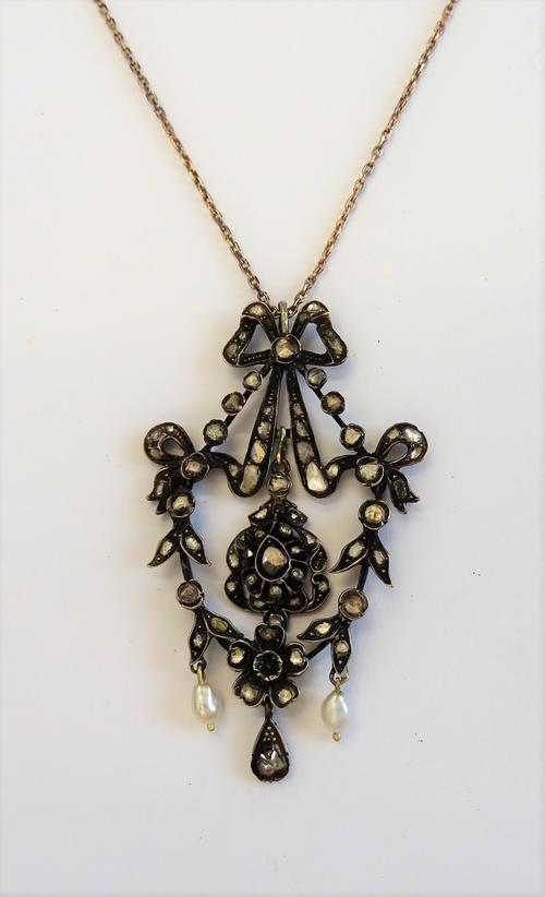 A rose diamond and cultured pearl pendant, in a pierced openwork foliate design, having bow motifs and with two cultured pearl drops, otherwise set wi