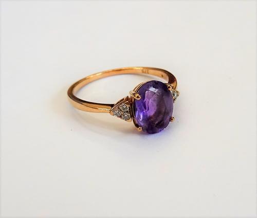 A gold, amethyst and diamond ring, claw set with the oval cut amethyst to the centre, between circular cut diamond set three stone shoulders, detailed