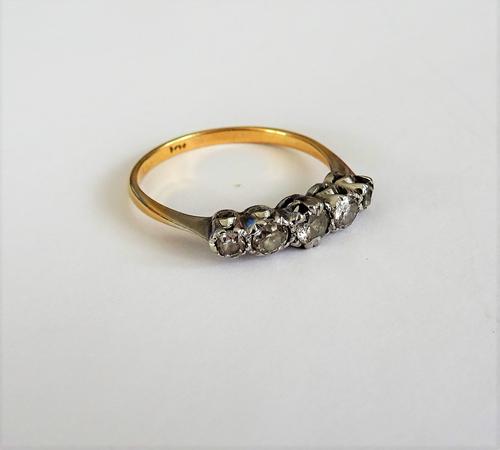 A gold and diamond set five stone ring, mounted with a row of graduated cushion shaped diamonds, the marks rubbed, ring size N, with a case.