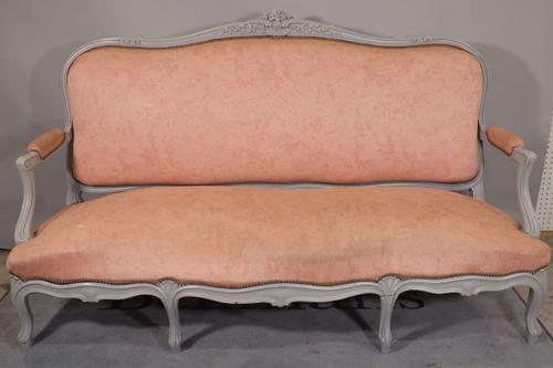 A Louis XV style open arm sofa with grey painted floral and shell moulded frame and serpentine seat on scroll supports, 185cm wide x 110cm high.